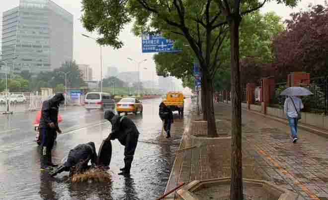 图3：7月18日，在北京市中关村北四环西路，中关村街道工作人员清扫积水，打开下水井盖加速排水.jpg